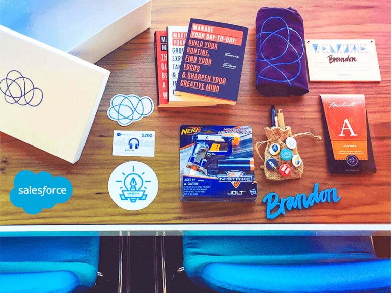 A desk with various books and swag with brand names printed on the front.