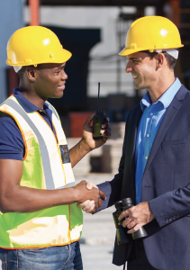 Two men with construction hats shaking hands.