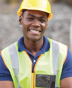 A smiling man with a construction hat and vest.